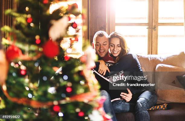 paar lesen ein buch über weihnachten im wohnzimmer - love magazine stock-fotos und bilder