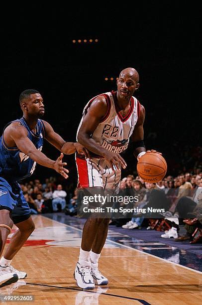 Clyde Drexler of the Houston Rockets moves the ball past Calbert Cheaney of the Washington Wizards during the game on December 27, 1997 at the Compaq...