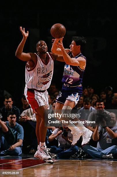 John Stockton of the Utah Jazz passes around Othella Harrington of the Houston Rockets during the game on January 10, 1998 at the Compaq Center in...