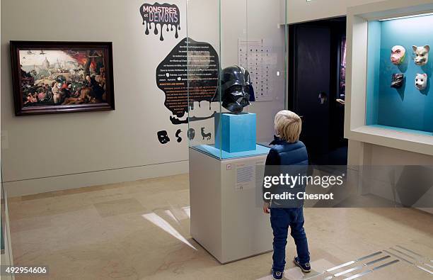 Kid looks at a mask of the Star Wars character Darth Vader during the exhibition "Mythes Fondateurs : D'Hercule a Dark Vador" at Petite Galerie du...