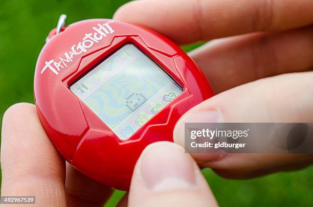 spielt mit tamagotchi - tamagotchi stock-fotos und bilder