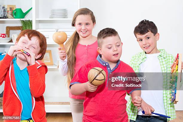 disabled child with friends playing musical instruments - maracas stockfoto's en -beelden