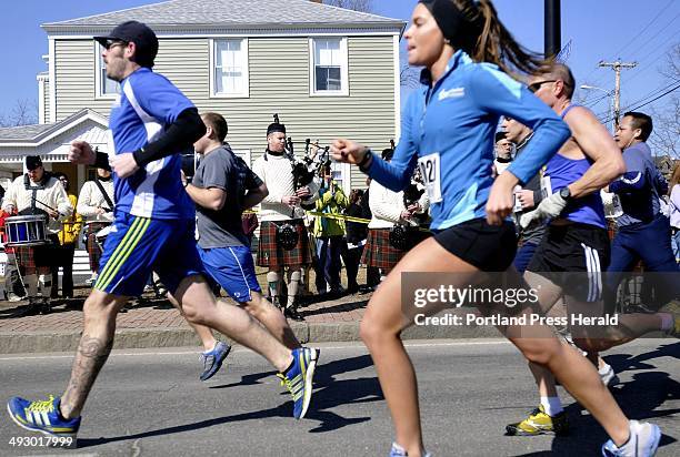 Runners make their way down Main St. In Saco past the Claddagh Mhor Pipe Band during Mary's Walk and the Kerrymen Pub 5K road race in Saco Sunday,...