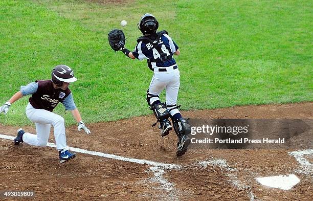 Saco baserunner Luke Chessie beats the throw to Bayside catcher Owen Burke to score a run on a triple by teammate Brogan Searle-Belanger to put their...