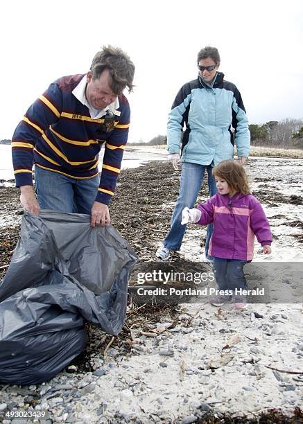 Derrick Daly, left, head gardener at the Inn By The Sea in Cape Elizabeth, holds a bag open for two year-old Kate Hetrick to throw away trash as her...