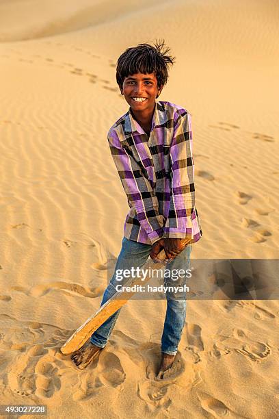 young indian boy playing cricket on sand dunes, india - rajasthani youth stockfoto's en -beelden