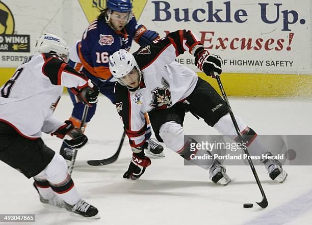 Portland Pirates' Maxim Goncharov, , center, joined by Jordan Martinook, , left, hold onto the puck while being pursued by Bridgeport Sound Tigers'...