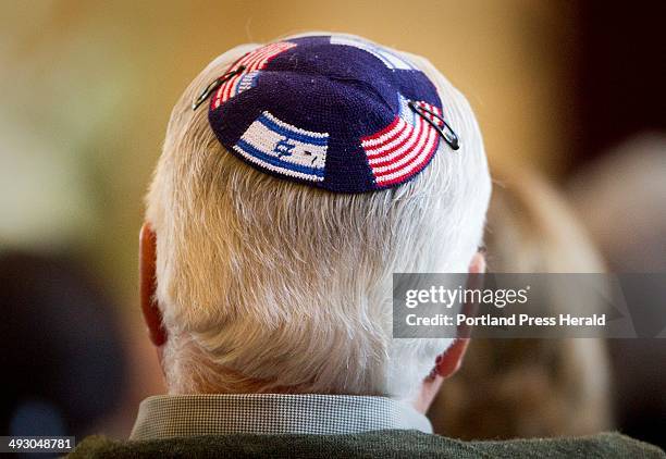 Wearing a yamaka with Israeli and American flags, an attendant at Temple Beth El in Portland listens to Senator Susan Collins speaks about a strong...