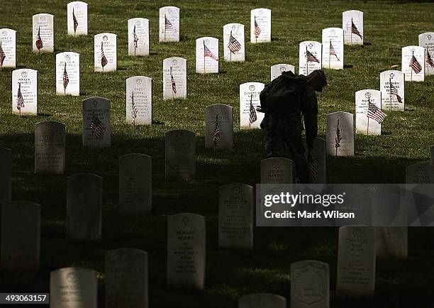 Member of the 3rd U.S. Infantry Regiment, 'The Old Guard,' places a flag at grave site during the 'Flags-In' ceremony May 24, 2014 at Arlington...