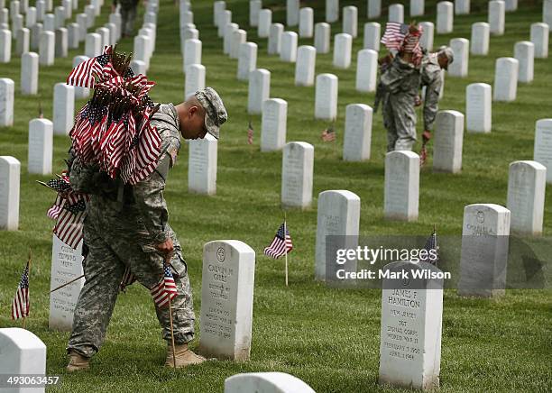 Members of the 3rd U.S. Infantry Regiment, 'The Old Guard,' place flags at grave sites during the 'Flags-In' ceremony May 24, 2014 at Arlington...