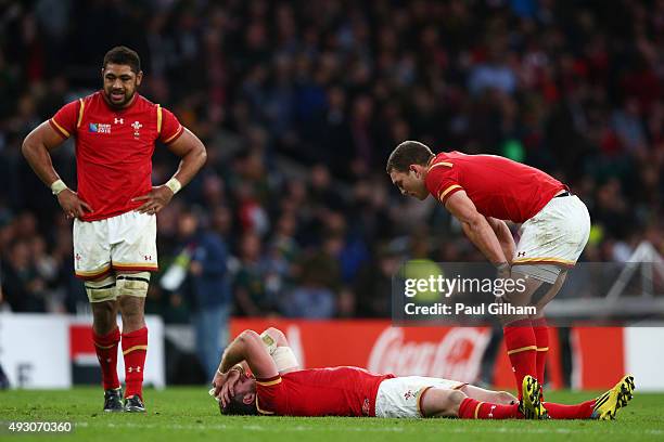 Alex Cuthbert of Wales lies dejected on the pitch as George North of Wales stands over him with Taulupe Faletau of Wales looking on during the 2015...