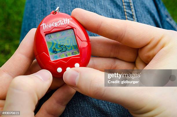 feeding a tamagotchi - tamagotchi stock pictures, royalty-free photos & images