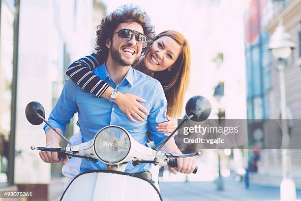 cheerful young couple riding on a motorbike. - couple scooter stock pictures, royalty-free photos & images