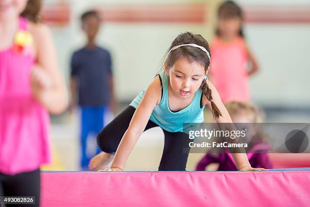 little girl crawling over the mat - tumbling gymnastics stock pictures, royalty-free photos & images
