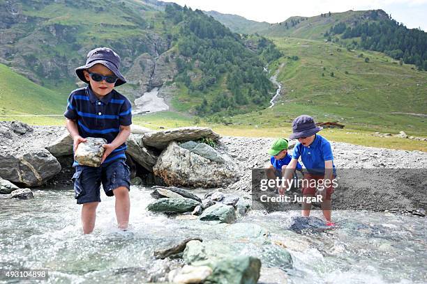 enfants de construire un barrage de la rivière dans les montagnes suisses - kids at river photos et images de collection