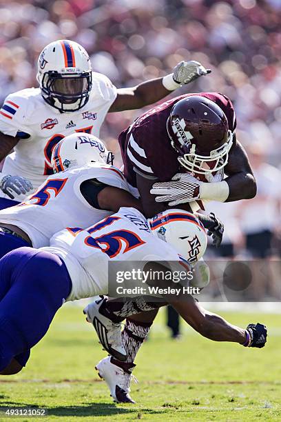 De'Runnya Wilson of the Mississippi State Bulldogs runs the ball and is hit by Lyn Clark and Desmond Lacey of the Northwestern State Demons at Davis...
