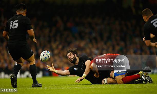Sam Whitelock of New Zealand offloads despite the tackle of Nicolas Mas of France during the 2015 Rugby World Cup Quarter Final match between New...