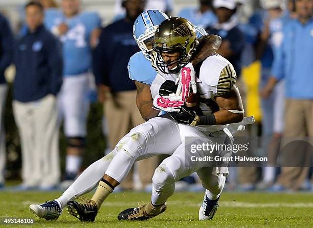 Chuck Wade of the Wake Forest Demon Deacons makes a catch as Mike Hughes of the North Carolina Tar Heels defends during their game at Kenan Stadium...