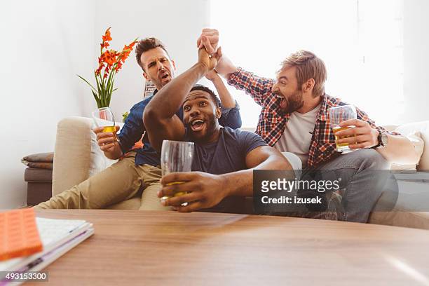 three excited guys watching sport on tv - championship round three stockfoto's en -beelden