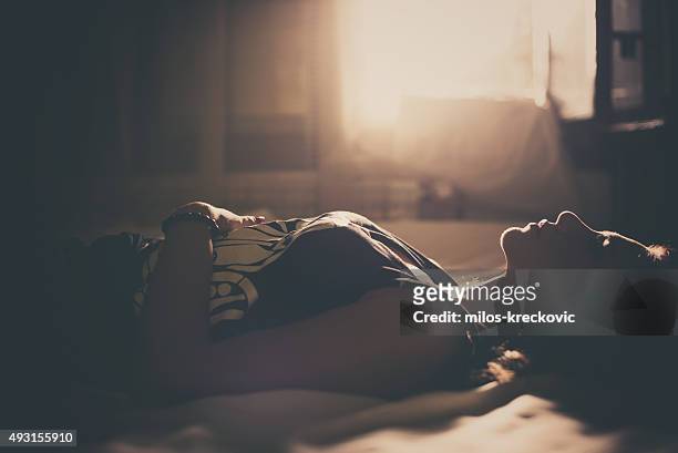 traurige mädchen liegen im bett - a lonely woman stock-fotos und bilder