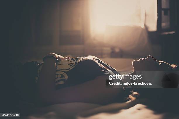 sad girl lying in bed - portrait dark background stock pictures, royalty-free photos & images