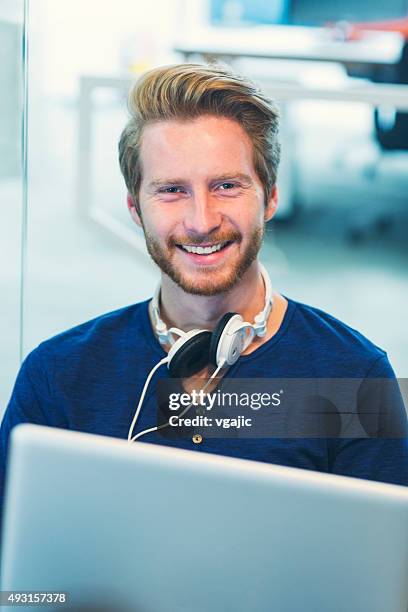 young man with headphones using his laptop. - headphone man on neck stockfoto's en -beelden