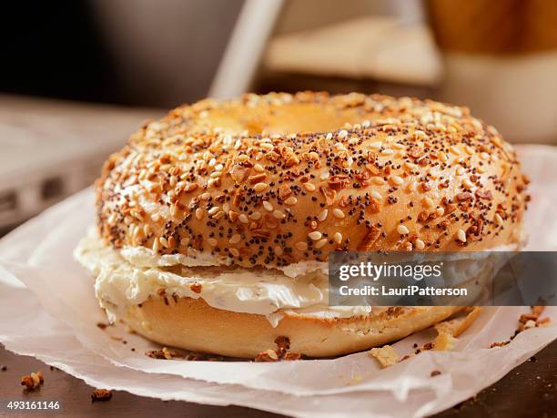 geröstete bagels mit frischkäse auf ihrem schreibtisch - sesam stock-fotos und bilder