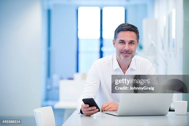 portrait of a confident businessman sitting at laptop - johnny stark stock pictures, royalty-free photos & images