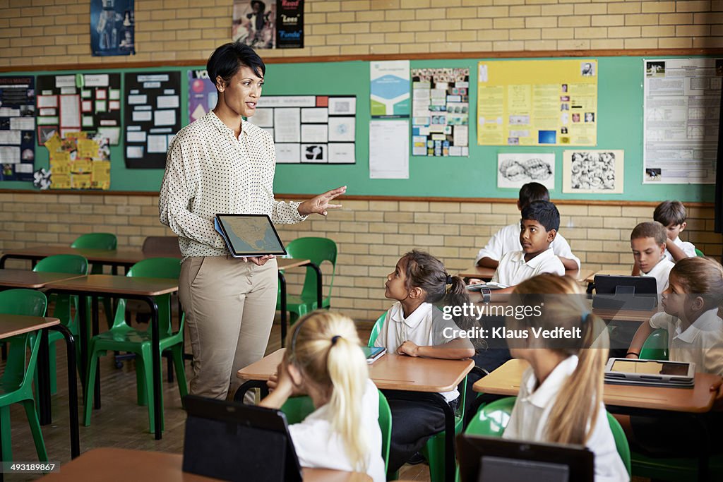 Teacher with tablet interacting with kids in class