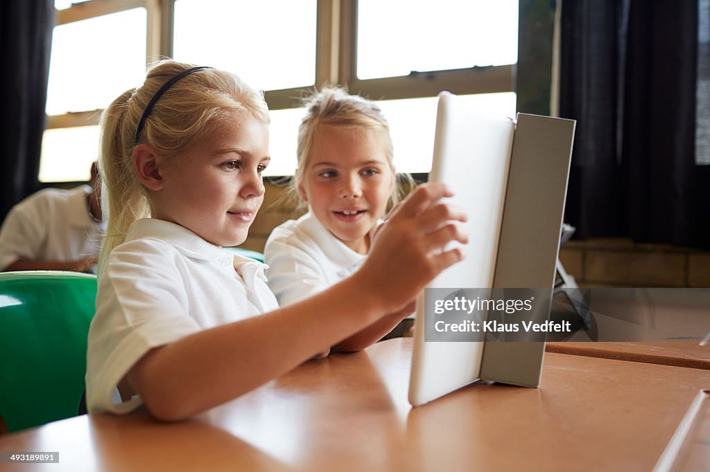 Schoolgirls looking at tablet in classroom