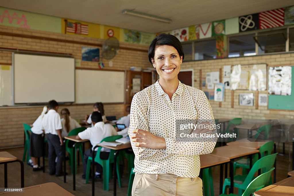 Teacher standing in classroom and smiling