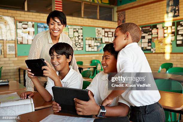 teacher and students looking at tablet - teacher desk fotografías e imágenes de stock