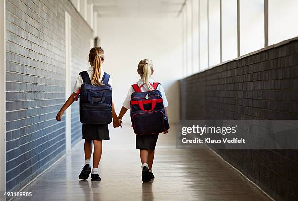 schoolgirls walking hand in hand at school isle - sac à dos enfant photos et images de collection