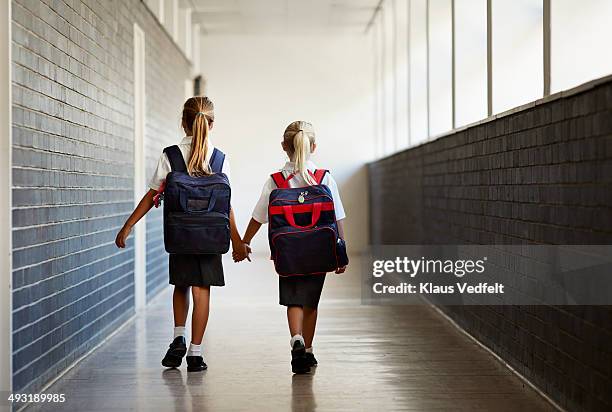 schoolgirls walking hand in hand at school isle - walking to school stock pictures, royalty-free photos & images