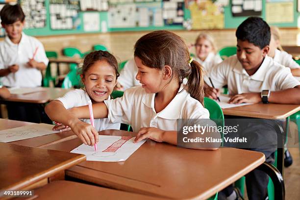 schoolgirls drawing on each others paper - aprender fotografías e imágenes de stock