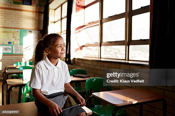 schoolgirl looking out of window of classroom - african child girl stock-fotos und bilder