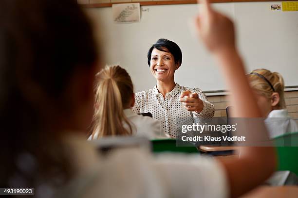 teacher in class picking student with raised hand - enseignante photos et images de collection