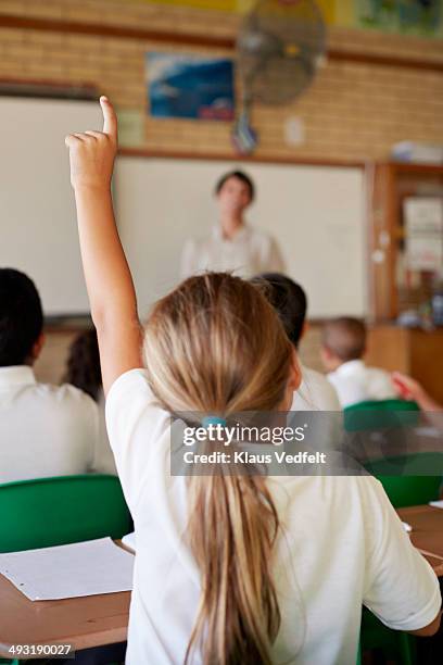 student with raised hand in classroom - schoolgirl photos et images de collection