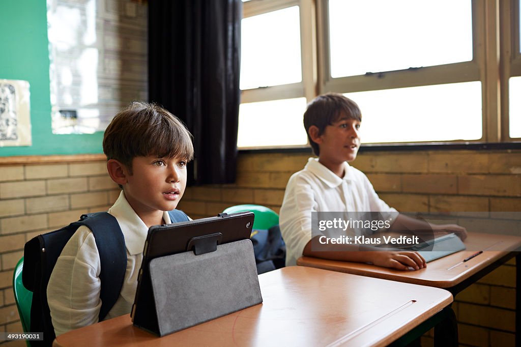 Kids sitting by desks in school