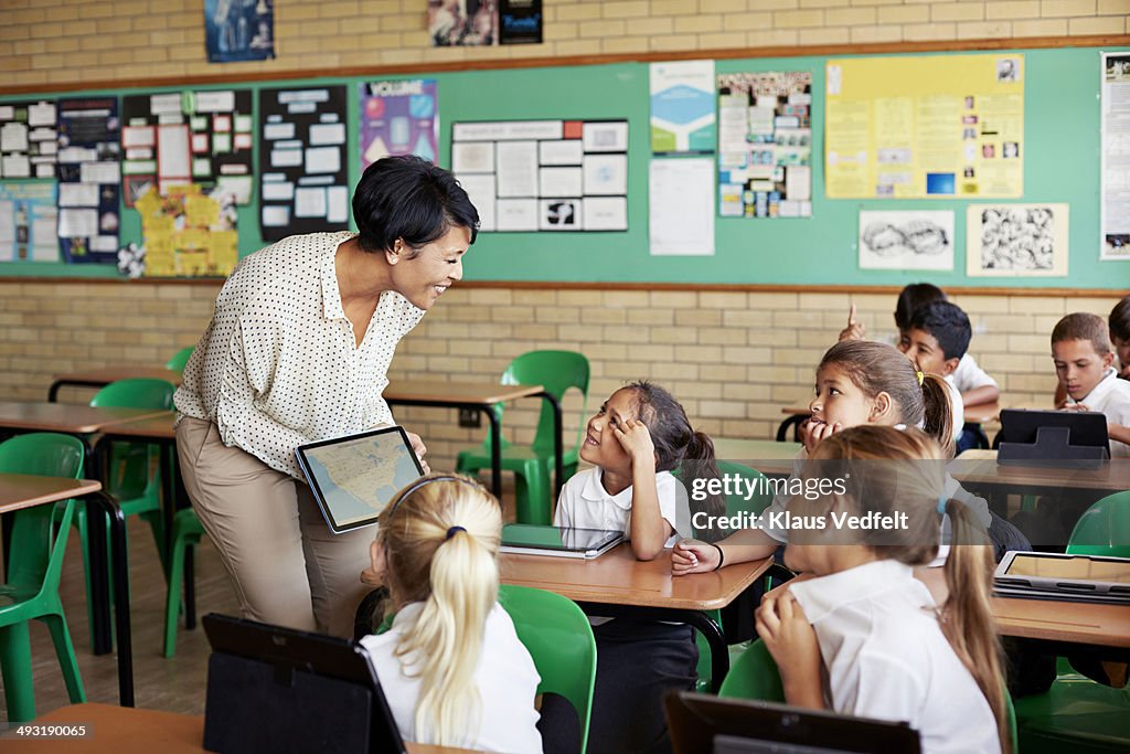 Teacher interacting with kids in class with tablet