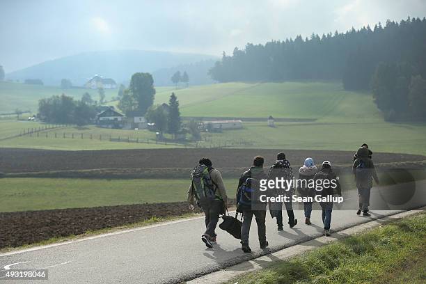 Migrants who had arrived via buses chartered by Austrian authorities walk towards the border to Germany on October 17, 2015 near Fuchsoedt, Austria....