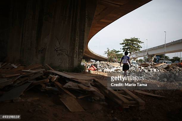 Viviane Sabino de Souza walks with her cart while searching for recyclable metal near her makeshift dwelling on a stretch of the Transcarioca BRT...