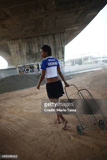 Viviane Sabino de Souza walks with her cart while searching for recyclable metal near her makeshift dwelling beneath a stretch of the Transcarioca...