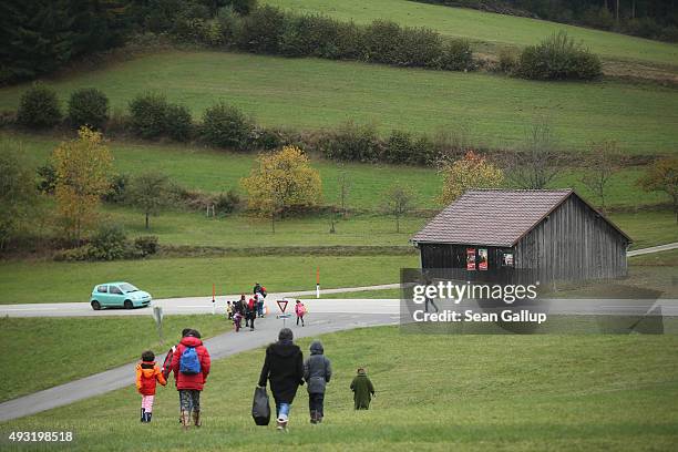 Migrants who had arrived on buses chartered by Austrian authorities walk towards the nearby border to Germany on October 17, 2015 in Kollerschlag,...