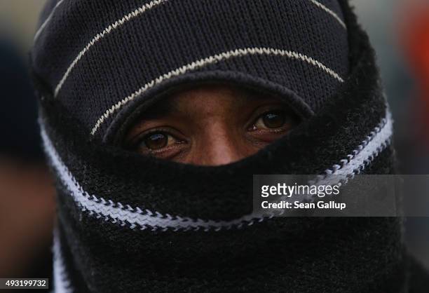 Migrant from Pakistan who had arrived on a bus chartered by Austrian authorities wraps his face in a scarf against the cold before continuing towards...