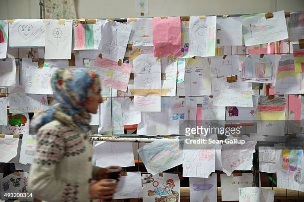 Migrant wearing a headscarf walks past a board decorated with drawings left by migrant children at a temporary shelter for migrants on October 17,...