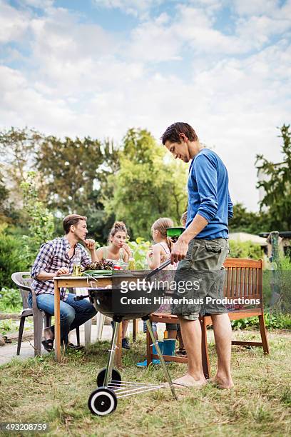 family at barbeque in garden - garden barbecue stockfoto's en -beelden