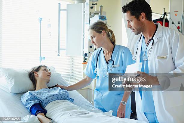 doctors talking to patient in hospital icu - krankenbett gespräch stock-fotos und bilder