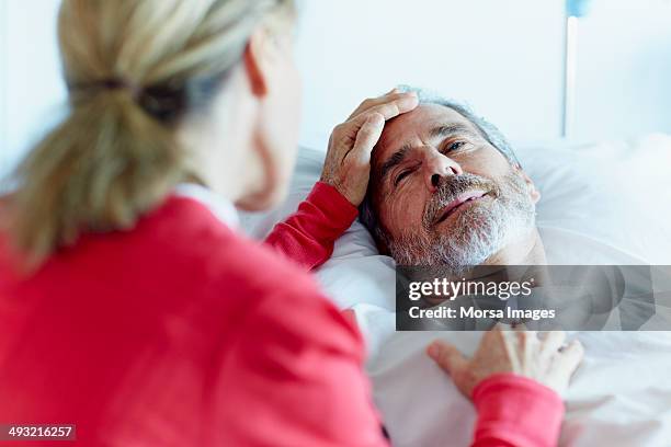 woman caressing ill man in hospital ward - visiting patient in hospital stock pictures, royalty-free photos & images