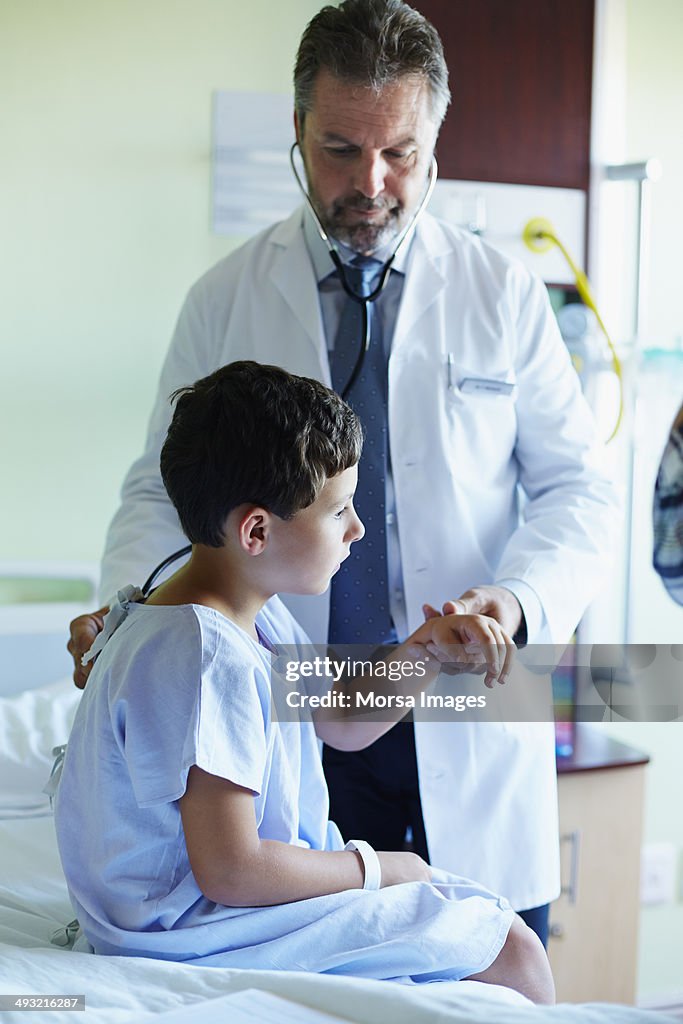 Doctor examining boy in hospital ward